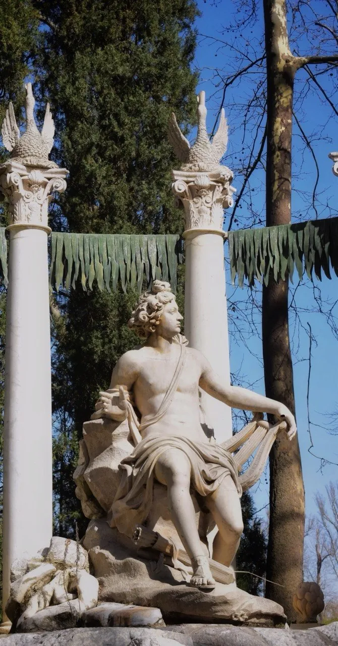 Estatua clásica entre columnas en un jardín