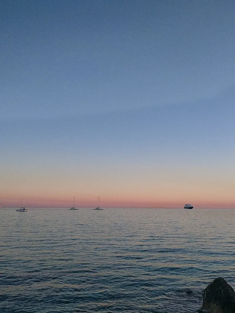 Mar en calma con veleros al atardecer